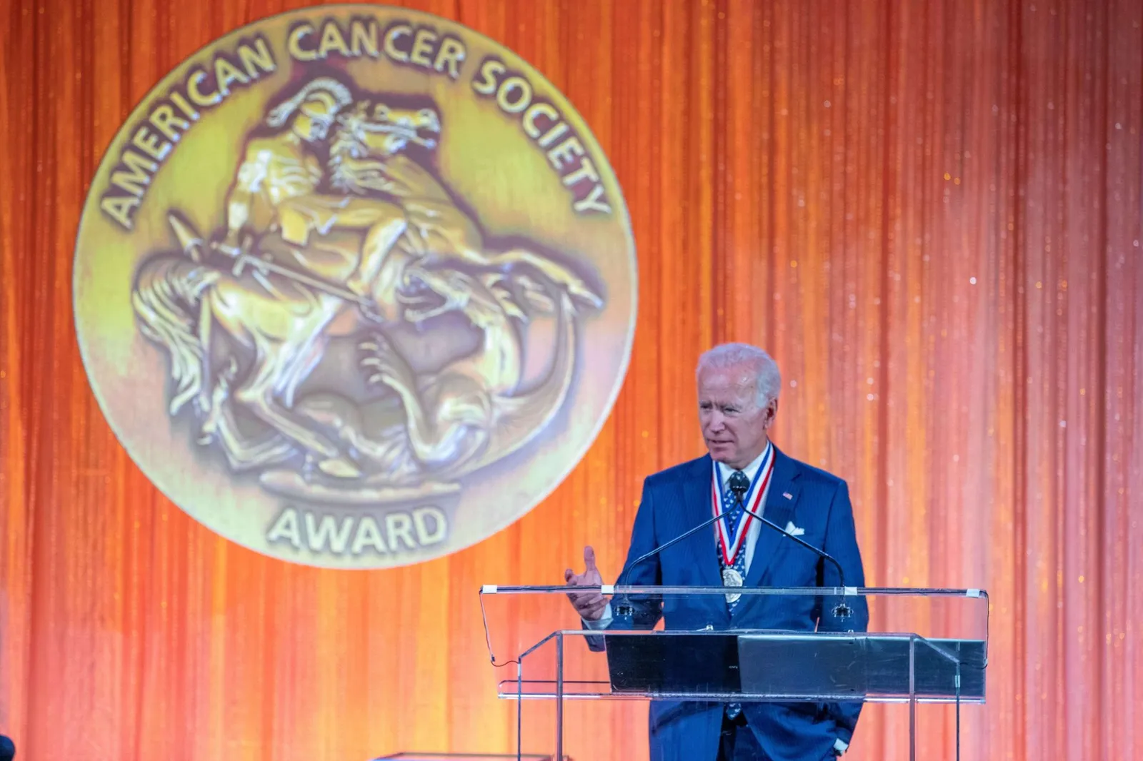 Joe Biden speaking at the podium beneath the American Cancer Society Medal of Honor seal, nonprofit gala coverage by Network Frequency