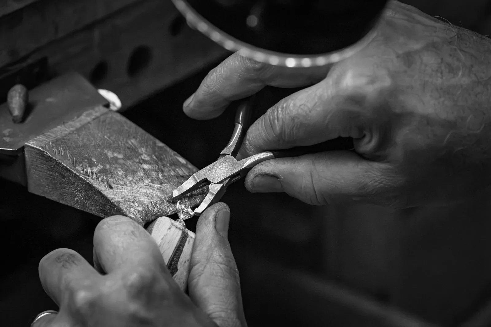 Close up of a jeweler's hands working a piece with hand tools
