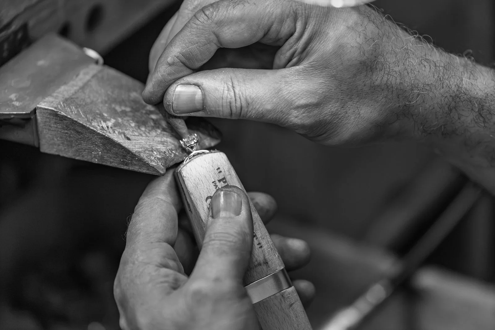 A jeweler files and shapes a ring at the workbench