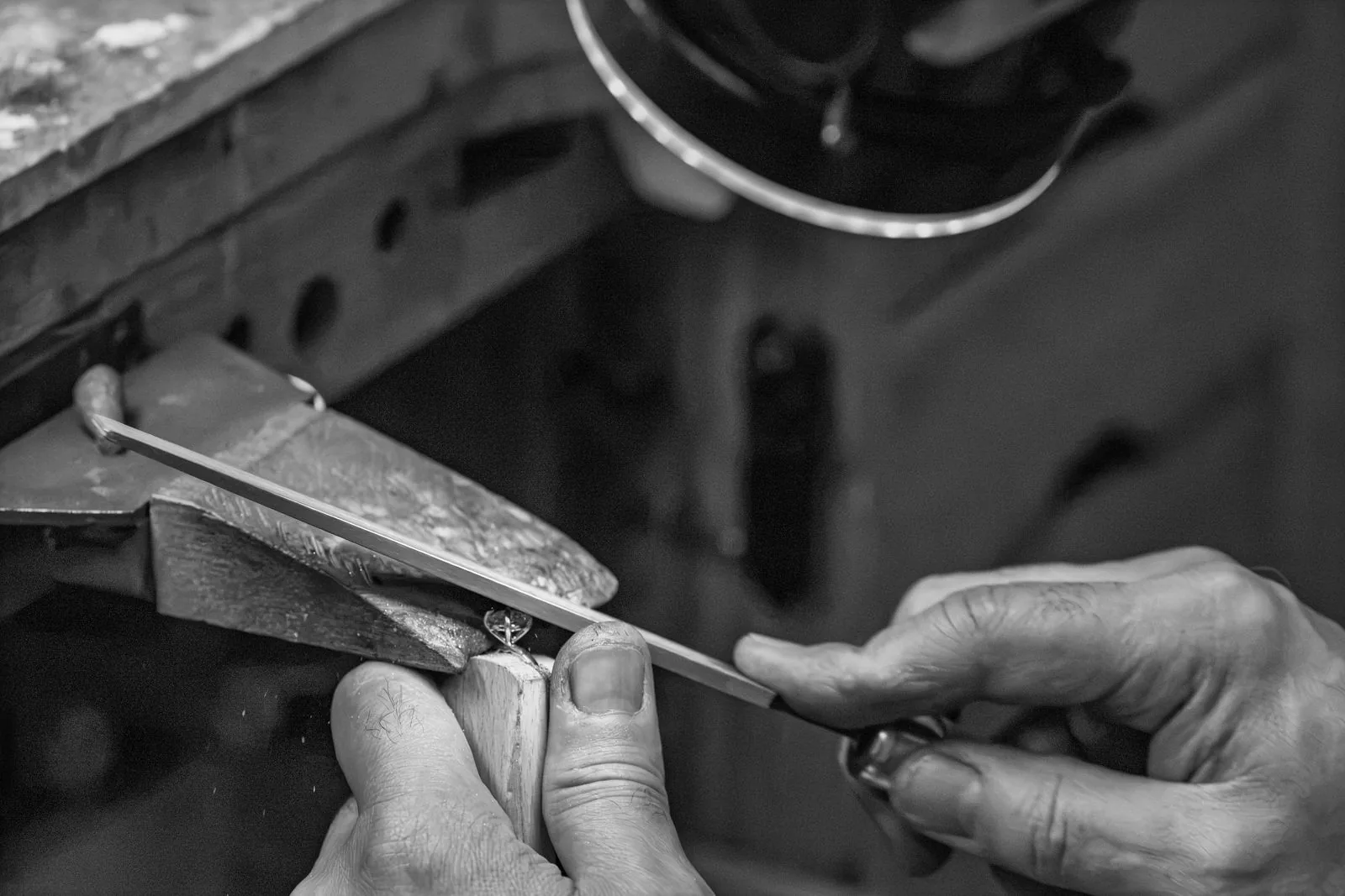 A jeweler applies flame to a gold ring at the bench, close up