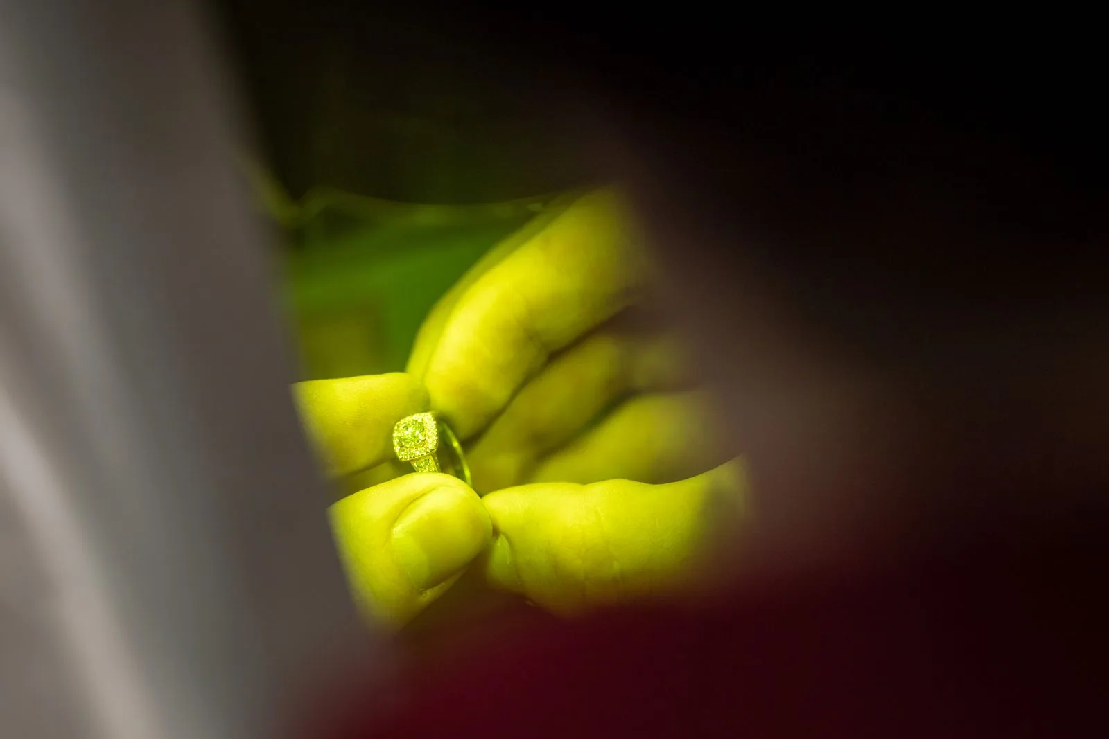 A yellow gemstone glowing under controlled light, held in the fingers