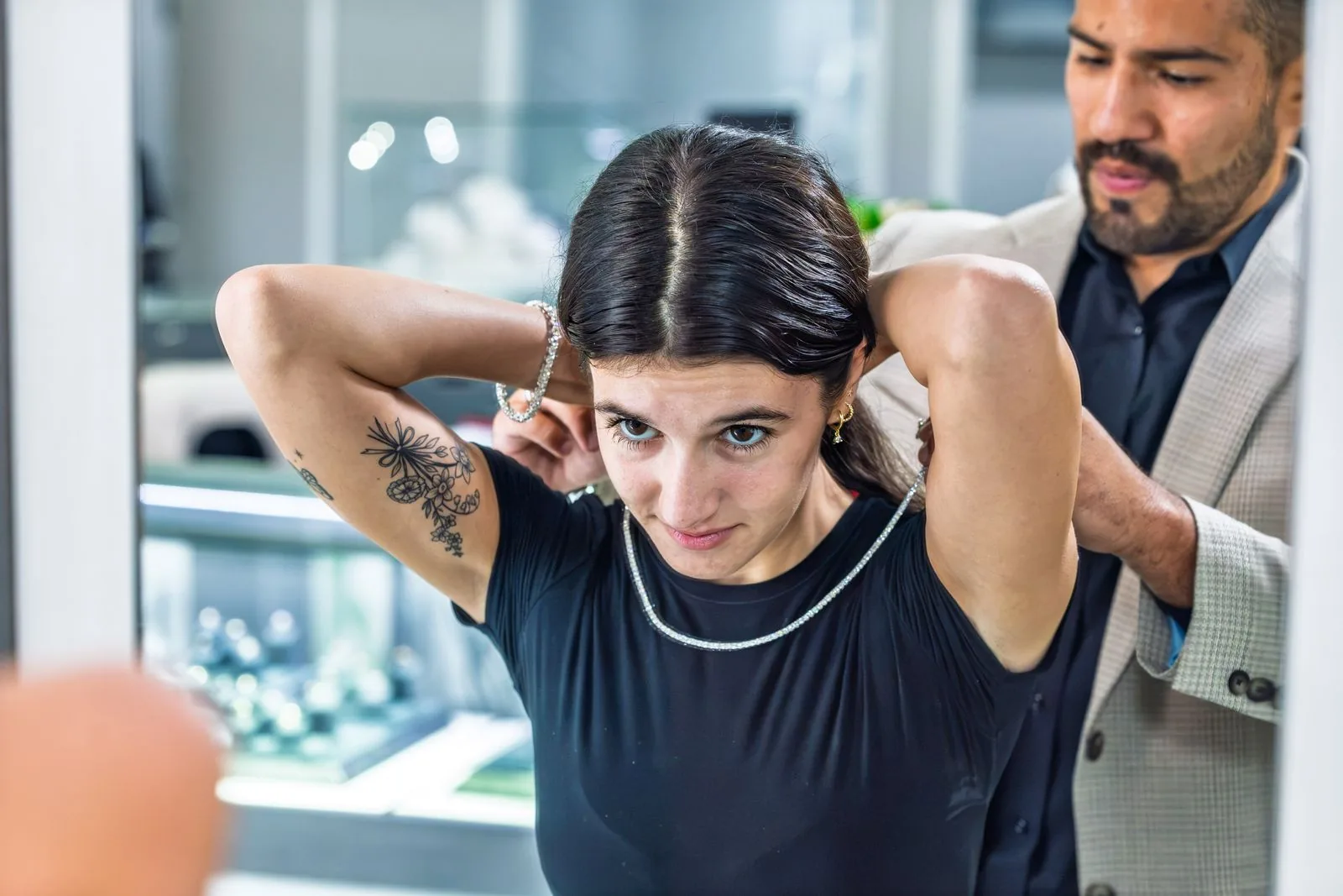 An associate helping a client fasten a necklace at the case